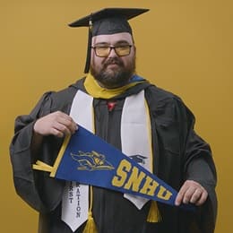 Frank Milisi, an SNHU graduate with a bachelor's in computer information systems, holding an SNHU pennant.