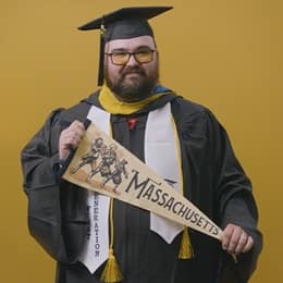 Frank Milisi, an SNHU graduate with a bachelor's in computer information systems, holding a Massachusetts state pennant.