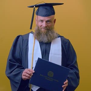 Gerald Pruitt '25, operations management with a concentration in project management from SNHU, holding a diploma cover.