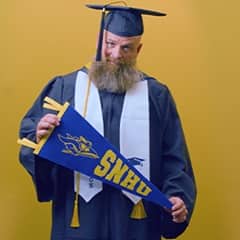 Gerald Pruitt '25, operations management with a concentration in project management from SNHU, holding an SNHU pennant.