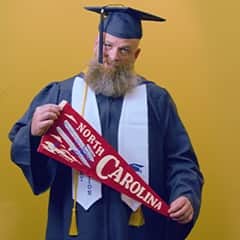Gerald Pruitt '25, operations management with a concentration in project management from SNHU, holding a North Carolina pennant.