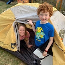 From left to right: Sara and Cam Telfer in a tent, participating in a SleepOut to show solidarity for people experiencing homelessness.