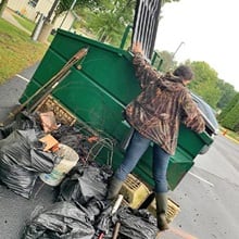 Kaytlin Perry ’21 putting trash collected after a neighborhood clean-up into a dumpster.