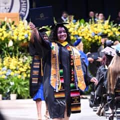 SNHU graduate holding up her diploma celebtating at 2025 spring Commencement 