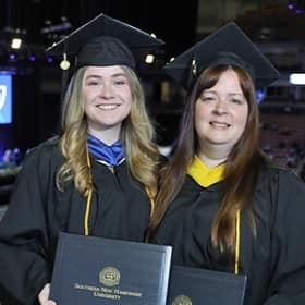 Heather and Kayleigh Maier holding their diplomas at the SNHU graduation