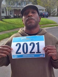 5K participant Travis Coley holding a sign with the text 2021