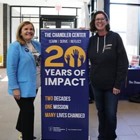 President Lisa Marsh Ryerson and Elizabeth Richards posing with The Chandler Center’s 20th anniversary banner.