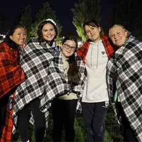 5 SNHU community members outside at night, wrapped in red and white checkered blankets.