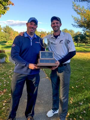 Two men holding a golf trophy at SNHU homecoming weekend.