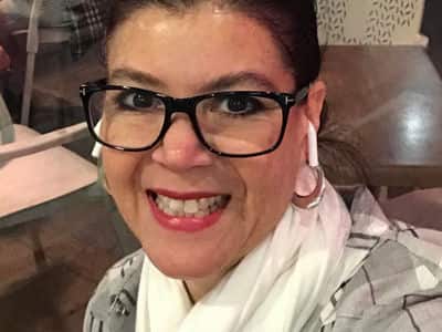 Doris Araujo, an adjunct faculty member in SNHU's online graphic design program, wearing eyeglasses, hoop earrings and a white scarf.