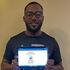 Jerron Trice, an SNHU bachelor's in business administration graduate, holding "Hidden Potential" by Adam Grant.
