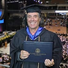 John Reck dressed in a graduation cap and gown