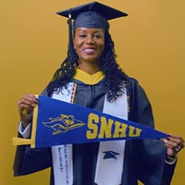 Kyla Johnson-Curtis, a 2025 SNHU grad who earn her bachelor's in operations management with a concentration in logistics and transportation holding a SNHU flag in front of a yellow background.