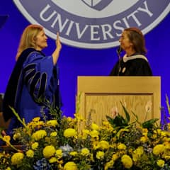 President Lisa Marsh Ryerson taking oath on stage with her right hand up at inauguration ceremony.
