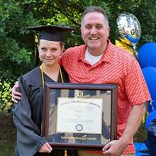 Loretta Gray holding her SNHU diploma with husband Cameron Gray.