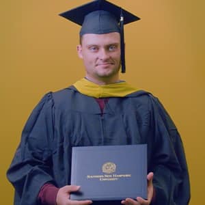 Luke Blaeser, a 2025 SNHU grad who earned his master's in healthcare administration holding his diploma in front of a yellow background.