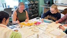 Four students painting tote bags in the Makerspace