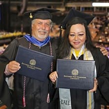 Michael Riley (left) and Marlene Riley (right) dressed in graduation caps and gowns