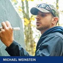 Michael Weinstein writing on a chalkboard with the text Michael Weinstein