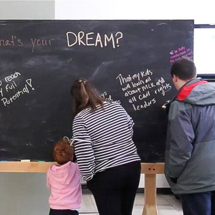 Attendee's of SNHU's MLK breakfast writing on a blackboard