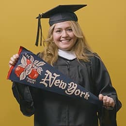 Nelly Bernal, a 2025 graduate who earned her BA in General Studies at SNHU holding a New York flag.