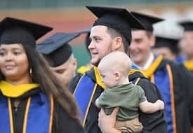 A snhu graduate holding a baby