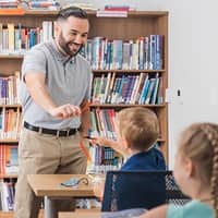 A student and a learner playing with art supplies in a classroom.
