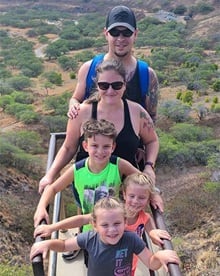 Heather Poss with her husband and three children on a hike standing at the top of a mountain