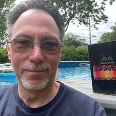 Paul Witcover, an associate dean of online MFA programs at SNHU, holding "Little, Big" by John Crowley.
