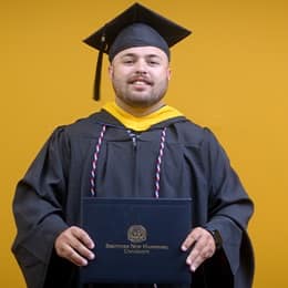 Payton Good, a 2025 SNHU graduate who earned his bachelor's in operations management wearing his cap and gown in front of a yellow background.