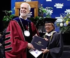 Camille MacIsaac, right, receiving her diploma from SNHU President Paul LeBlanc, left, at a Commencement ceremony. 