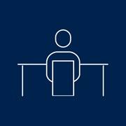 A blue icon of a person working at a desk 