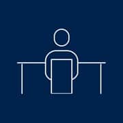 A blue icon of a person working at a desk