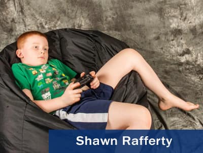 Photo of a boy sitting in a beanbag chair and playing a video game taken by Shawn Rafferty.