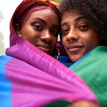 Two women wrapped in a pride flag