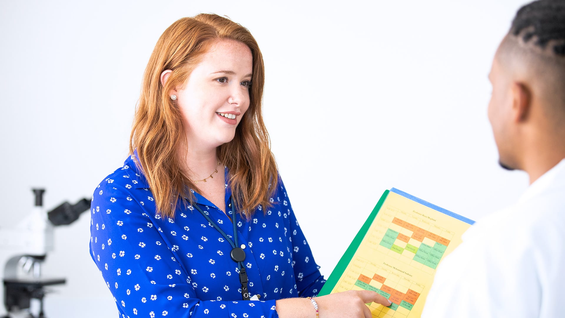 Ali Lamoureux-Rule, a 2022 healthcare admistration degree online graduate, pointing to a patient's chart in a medical office.