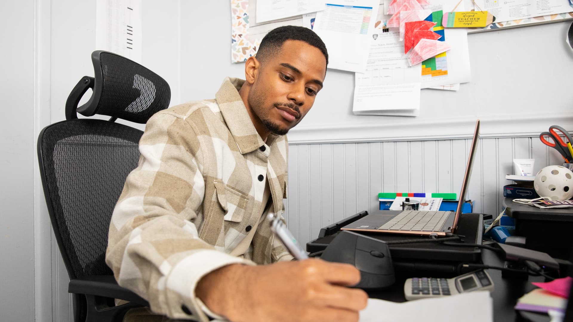 Keyon Tuiteleleapaga, a 2024 MS in Psychology online alum from SNHU, taking notes while on a work call.