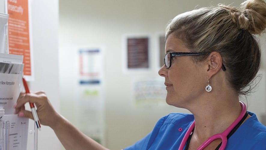 SNHU graduate Kristina Libby checking a wall of documents in a healthcare setting