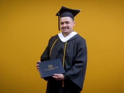 Anthony Fernandez, SNHU graduate with a bachelor's in political science holding his diploma.