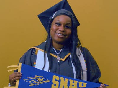 Jazzmen Shipp, a 2025 SNHU graduate who earned an associate degree in business administration holding a SNHU flag.