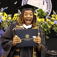 Shaquita Callier in her cap and gown holding her diploma after graduation 