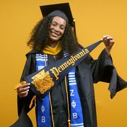 Shiqueta Dixon, a 2025 master's in healthcare administration graduate from SNHU, wearing a cap and gown and holding a Pennsylvania state flag.