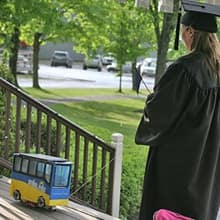 Fiona Mathiesen controlling a miniature version of the SNHU bus that is carrying her diploma.
