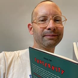 Ben Nugent, a professor of English on campus at SNHU and director of the Low-Residency MFA program holding his book 'Fraternity.'