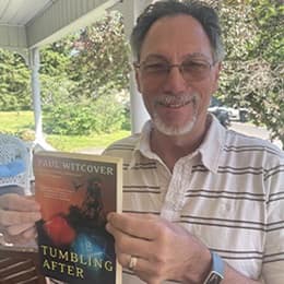 Paul Witcover, associate dean of the online MFA program at SNHU holding his book 'Tumbling After.'