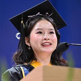 Tien Phan, a 2026 SNHU graduate with a bachelor's in marketing, speaking at her commencement ceremony.