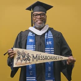 Tyrone R. Turner-Perry, an SNHU graduate with a bachelor's in communication, holding a Massachusetts state pennant.