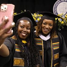 Shaquita Callier and Victoria White taking a selfie together with their cap and gowns on