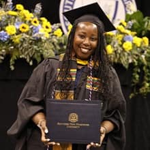 Victoria White with her cap and gown holding her diploma after graduation