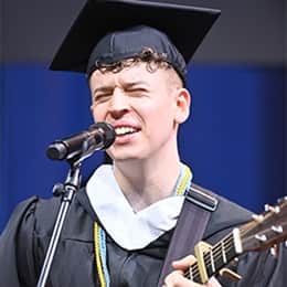Warren Games Olson, a 2026 SNHU graduate with a bachelor's in communication, performing the national anthem with a guitar.
